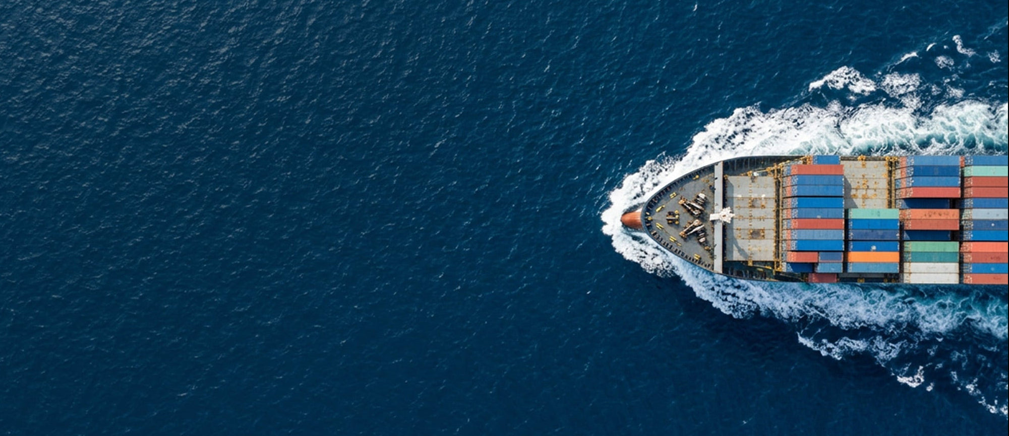 Container ship with colorful cargo containers sailing on a blue ocean.